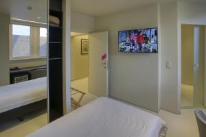 a bedroom with a bed and a tv on the wall at Auberge du Vieux Cedre in Enghien