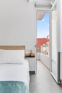 1 dormitorio con cama blanca y balcón en Open Sea Suites en Las Palmas de Gran Canaria