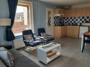 a living room with a couch and chairs and a kitchen at Appartementen Zandvoort in Zandvoort