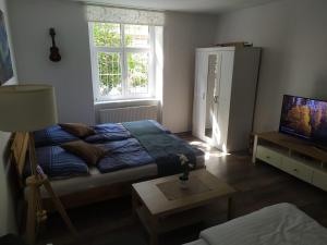 Schlafzimmer mit einem Bett, einem TV und einem Tisch in der Unterkunft PISQOR Apartment - self check-in in Bratislava