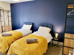 twee bedden in een kamer met een blauwe muur bij 5 Bedroom house in great location, near stadium NN5 in Upton
