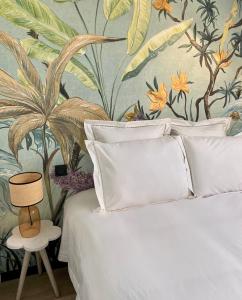 a bedroom with a white bed with a tropical wallpaper at Le trait d'Union le Croisic in Le Croisic