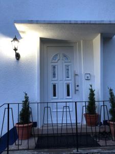 a white door on a white house with potted plants at Green Bambus Wohnung in Murrhardt