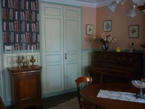 una habitación con una mesa y un piano y una habitación con libros en La Maison de Claire, en Val Couesnon