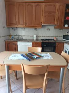 eine Küche mit Holzschränken und einem Tisch mit Stühlen in der Unterkunft Casa da Zi in Vila Nova de Milfontes