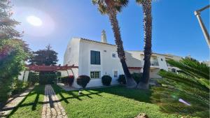a white house with palm trees in the yard at Vila Castro-Cleverdetails, Quiet area, private pool in Vilamoura