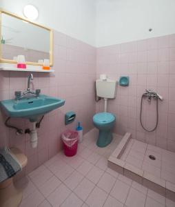 a pink bathroom with a sink and a toilet at Hotel Eleni Anagros in Archangelos