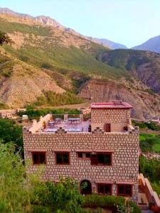 a brick building on a hill with mountains in the background at Toubkal Ecolodge in Imlil