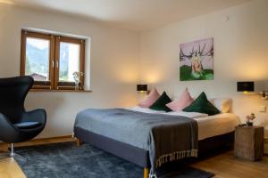 a bedroom with a bed and a chair and a window at Monte Vita Tirol - Apartments in Biberwier