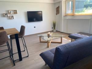 sala de estar con sofá azul y mesa de cristal en Le clos des Pommiers Fuji en Uffholtz