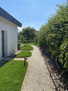 a walkway next to a building with grass and bushes at Le clos des Pommiers Fuji in Uffholtz