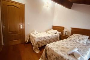 a bedroom with two beds with white sheets at Apartamentos Rurales LLeguera in Llanes