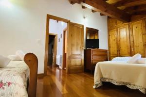 1 dormitorio con 2 camas y TV. en Apartamentos Rurales LLeguera en Llanes