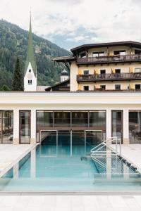 a building with a swimming pool in front of it at Hotel Bräu in Zell am Ziller