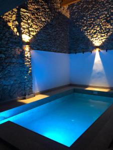 a swimming pool with blue lighting in a room with a stone wall at Beni Qásim 1915 in Benicàssim
