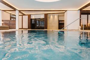 an indoor swimming pool with blue water in a building at Hotel Bräu in Zell am Ziller