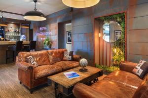 a living room with leather furniture and a bar at The Originals Boutique, Hôtel des Orangers, Cannes (Inter-Hotel) in Cannes