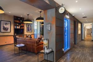 a living room with a couch and a clock on a wall at The Originals Boutique, Hôtel des Orangers, Cannes (Inter-Hotel) in Cannes