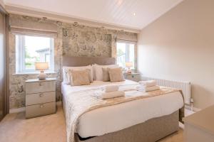 a bedroom with a large bed and two windows at Marshwiggle, Aldeburgh in Aldeburgh