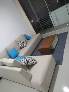 a living room with a white couch and blue pillows at Hermoso Departamento - Zona Miraflores in Tarija