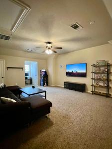 a living room with a couch and a flat screen tv at Luxury Legacy West Townhouse in Plano