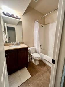 a bathroom with a toilet and a sink and a tub at Luxury Legacy West Townhouse in Plano