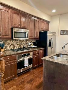 a kitchen with wooden cabinets and stainless steel appliances at Luxury Legacy West Townhouse in Plano