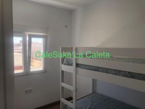 Pokój z łóżkiem piętrowym i oknem w obiekcie CaleSuka La Caleta w Kadyksie