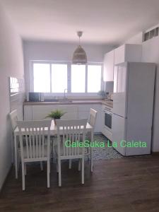 kuchnia ze stołem, krzesłami i lodówką w obiekcie CaleSuka La Caleta w Kadyksie