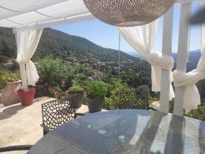una mesa y sillas en un balcón con vistas en A Casa Vadiiolina - Villa Radriimas d'exception en Sollacaro