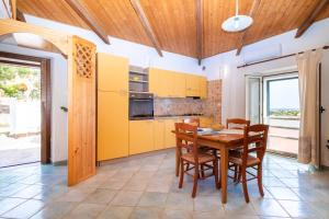 kuchnia z żółtymi szafkami oraz drewnianym stołem i krzesłami w obiekcie Reparata w mieście Capo Testa