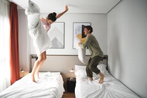 two women jumping on beds in a hotel room at Hotel Kramer in Valencia