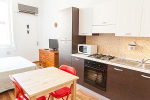 una cocina con armarios blancos y una mesa con sillas rojas en S Efisio in Cagliari Centre Q4825, en Cagliari