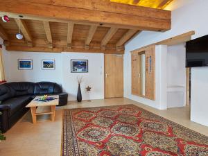 ein Wohnzimmer mit einem schwarzen Ledersofa und einem Tisch in der Unterkunft Appartement Alpenzauber in Längenfeld