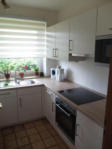eine Küche mit weißen Schränken, einem Waschbecken und einem Fenster in der Unterkunft Haus am Deich in Wittdün