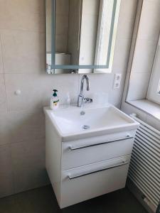 a white bathroom with a sink and a mirror at Haus-am-Deich in Wittdün
