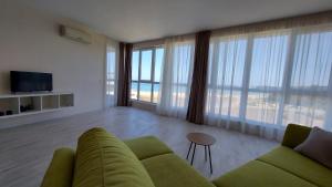 a living room with a green couch and large windows at Aparthotel Happy in Primorsko