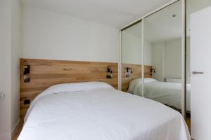 a bedroom with a white bed and a mirror at APARTAMENTOS NIZA in Santander