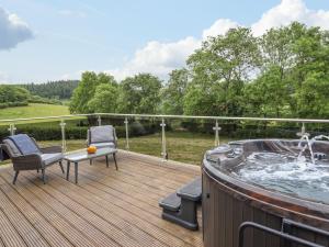 una terraza con jacuzzi y 2 sillas en The Cabin at Evelyns Retreat, en Corwen