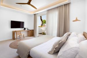 a white bedroom with a bed and a television at Maya Beach Resort in Massa Lubrense