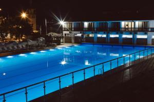 een zwembad 's nachts met lichten aan bij DEM Hotel in Soechoemi