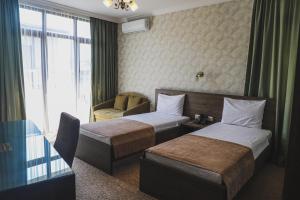 ein Hotelzimmer mit 2 Betten und einem Stuhl in der Unterkunft Old Garden Hotel Batumi in Batumi