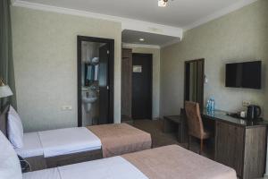 a hotel room with two beds and a desk at Old Garden Hotel Batumi in Batumi