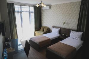 ein Hotelzimmer mit 2 Betten und einem Stuhl in der Unterkunft Old Garden Hotel Batumi in Batumi