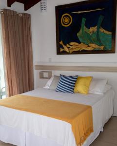 a bed in a bedroom with a painting on the wall at Hotel Maricá in Penha