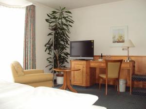 Zimmer mit einem Schreibtisch, einem TV und einem Bett in der Unterkunft Boardinghouse am Wall in Salzgitter-Bad