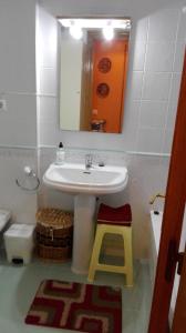 a bathroom with a sink and a mirror and a stool at Amplio Loft con plaza de garaje in Cangas de Onís
