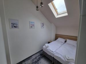 a bedroom with a bed with white sheets and a window at Domki Gold-Time Niechorze in Niechorze