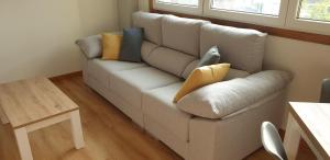 un sofá con almohadas en la sala de estar en Piso puerto Foz, en Foz