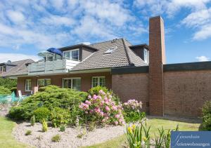 a brick house with flowers in front of it at Friesenhain Ferienwohnungen in Sankt Peter-Ording